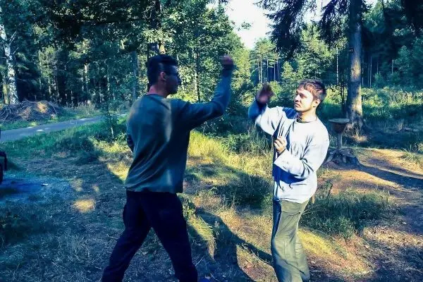 Zwei Personen üben eine Kampfsporttechnik im Wald