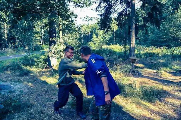 Zwei Personen üben eine Nahkampftechnik im Wald
