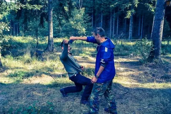 Zwei Personen üben eine Selbstverteidigungstechnik im Wald