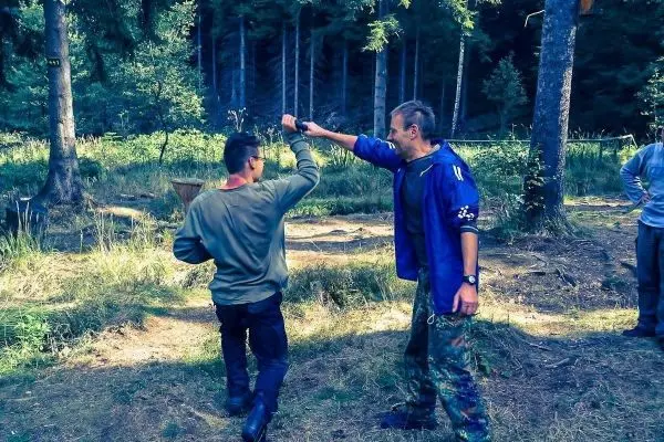 Zwei Personen üben eine Selbstverteidigungstechnik im Wald