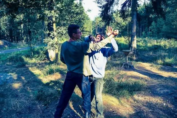 Zwei Personen üben eine Selbstverteidigungstechnik im Wald aus