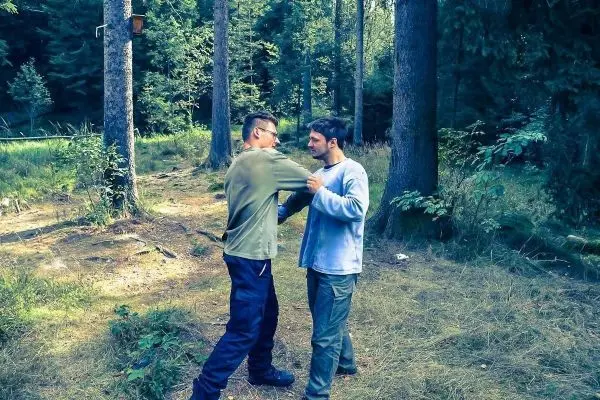 Zwei Personen üben eine Technik zur Selbstverteidigung im Wald