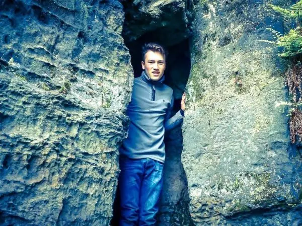 Junge steht zwischen zwei großen Felsen in einer Felsspalte