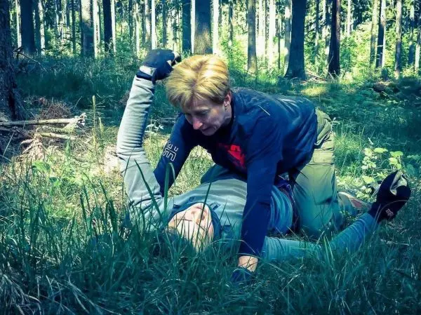 Kampfszenario im Wald, eine Person kontrolliert eine andere am Boden