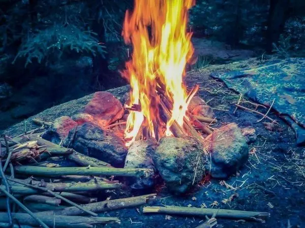 Kleine Flamme brennt zwischen Steinen auf dem Boden