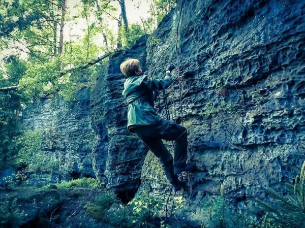 Klettert an einer Felswand mit einem Seil