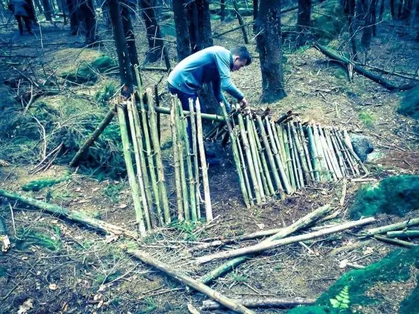 Mann baut eine improvisierte Konstruktion aus Ästen im Wald