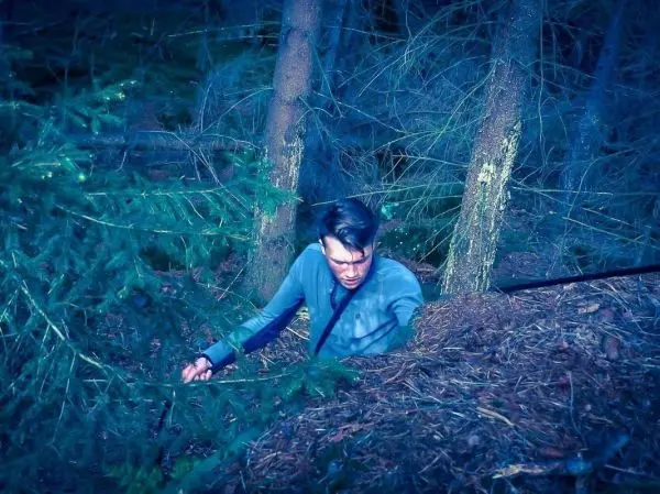 Mann bewegt sich durch dichte Unterholzschicht zwischen Bäumen