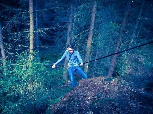 Mann überquert mit einem Seil eine steile Erhebung im Wald