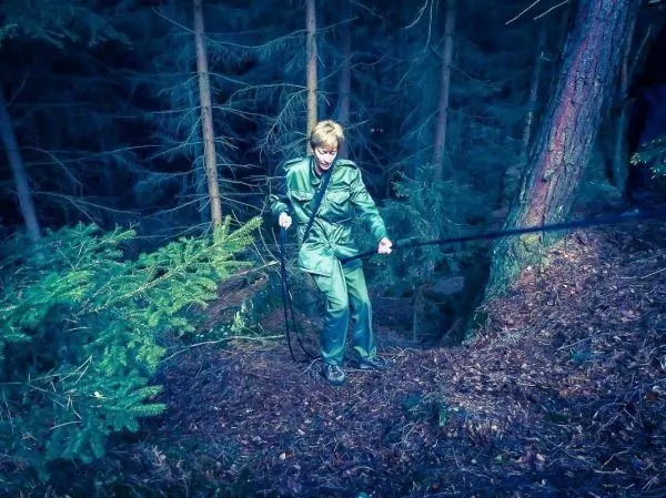 Person hält ein Seil und steht im Wald