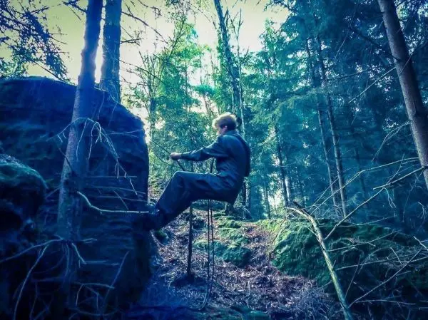 Person klettert an einer selbstgebauten Seilbrücke hoch im Wald