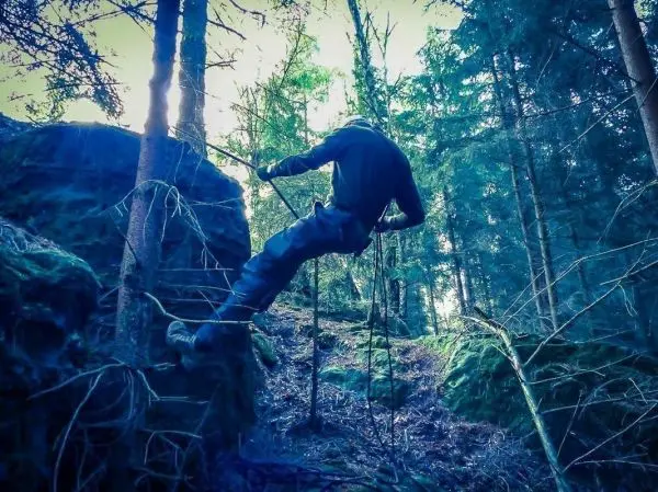 Person klettert an einer selbstgebauten Seilbrücke zwischen Bäumen