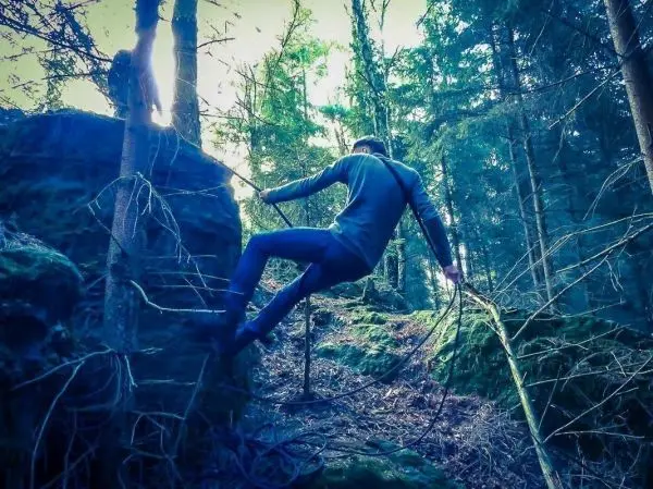 Person klettert über einen großen Felsen im Wald