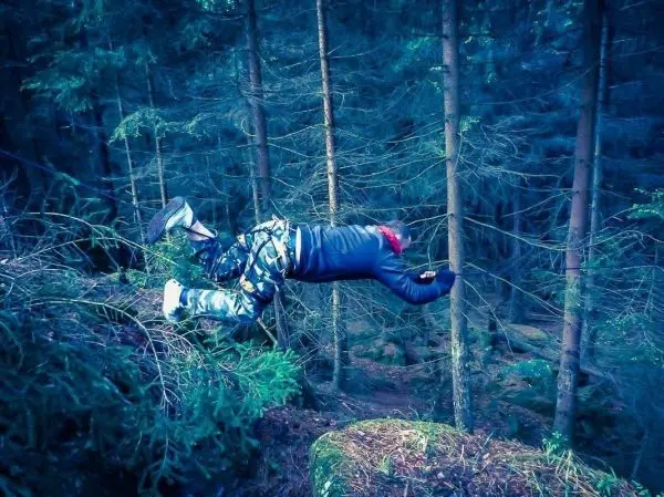 Person liegt auf einem Baumstamm im Wald
