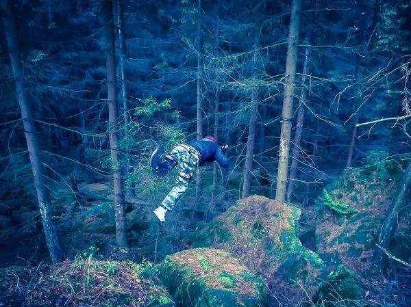Person springt von einem Felsen in den Wald