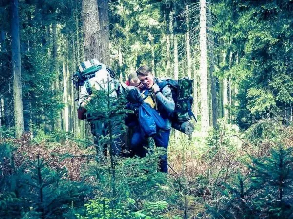 Person trägt Rucksack und schaut auf Karte im Wald beim Überlebenstraining