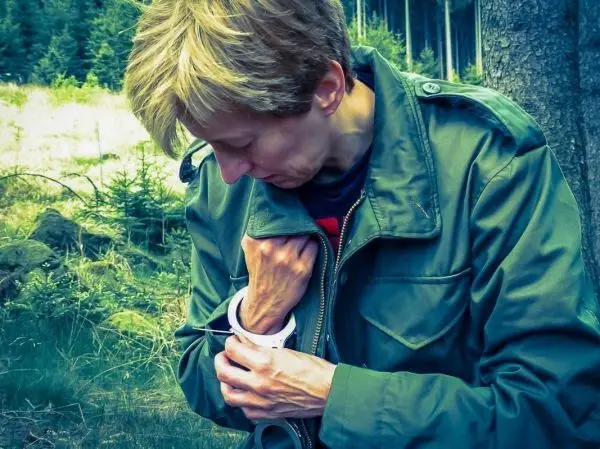 Person überprüft Handgelenk mit einem Armband im Wald