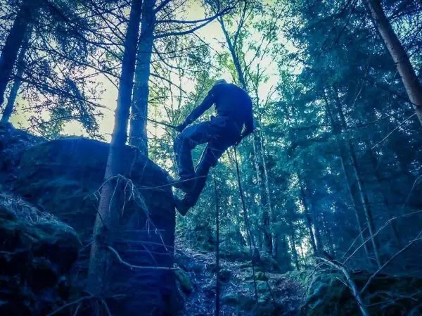 Person überquert einen großen Felsen im Wald
