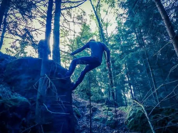 Person überquert Felsen mit zwei Stöcken im Wald