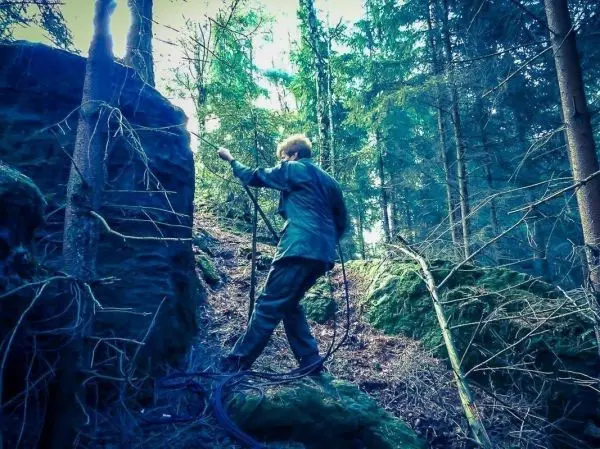 Person zieht ein Seil über einen Felsen im Wald