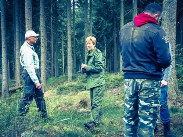 Personen stehen im Wald und betrachten Ausrüstung beim Überlebenstraining