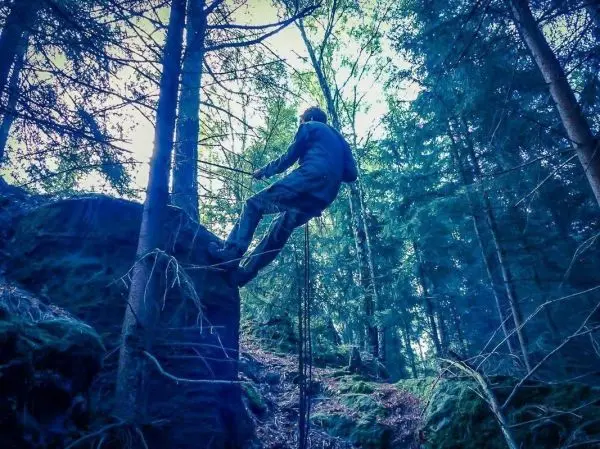Seilquerung an einem Felsen im Wald mit Seil und Kletterausrüstung