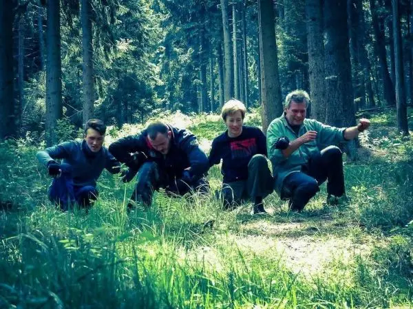 Vier Personen hocken im Wald und arbeiten am Boden mit Werkzeugen