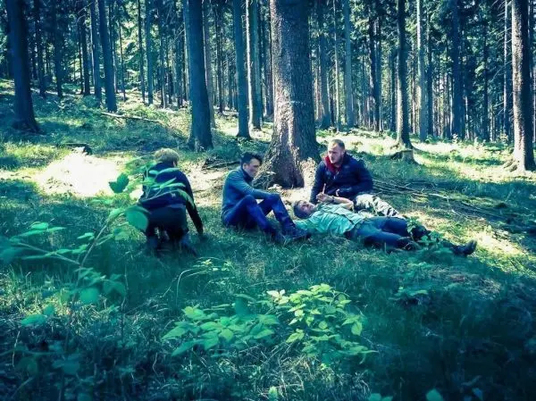 Vier Personen leisten Erste Hilfe im Wald, eine Person liegt am Boden