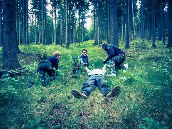 Vier Personen leisten Erste Hilfe in einem Waldgebiet