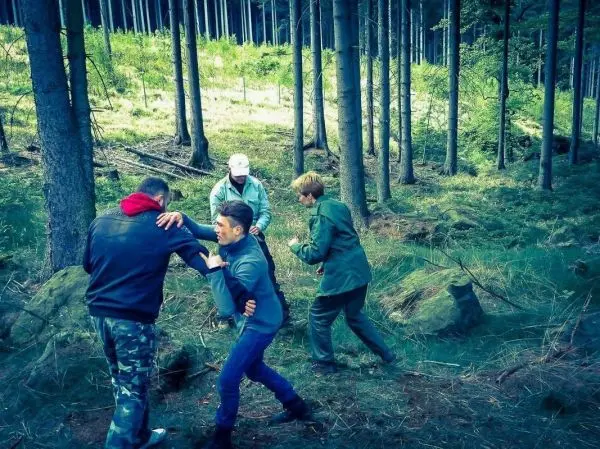 Vier Personen üben eine körperliche Auseinandersetzung im Wald