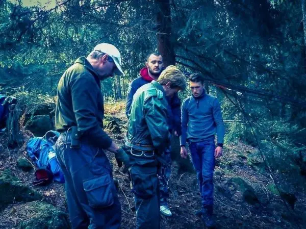 Vier Personen überprüfen Ausrüstung im Wald, während sie sich auf eine Aktivität vorbereiten