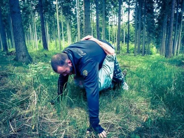 Zwei Personen in einer Kampfposition auf dem Boden im Wald