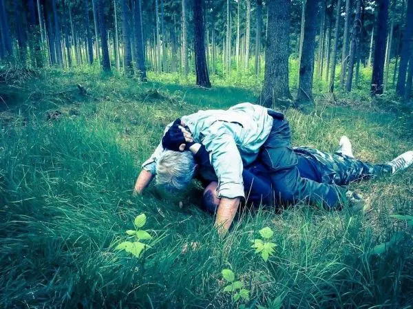 Zwei Personen liegen im Gras und führen eine körperliche Auseinandersetzung durch