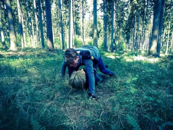 Zwei Personen liegen im Gras und scheinen zu ringen