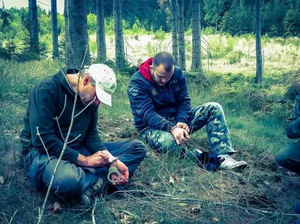 Zwei Personen sitzen im Wald auf dem Boden und sind gefesselt