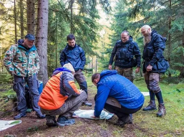 Gruppe betrachtet Karte im Wald beim Überlebenstraining
