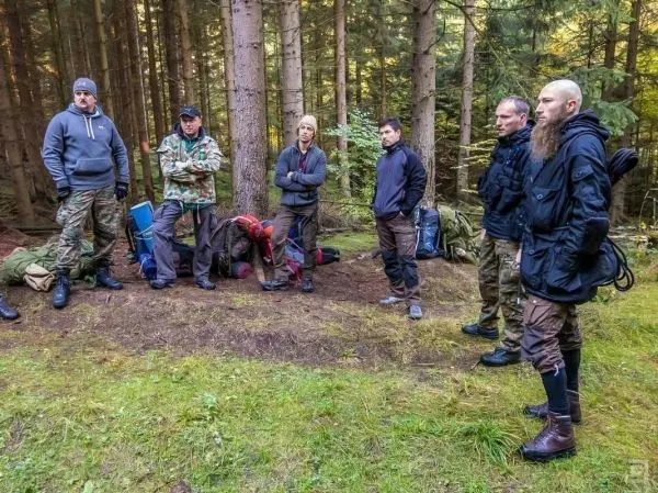Gruppe steht im Wald um Rucksäcke, während sie eine Besprechung hat