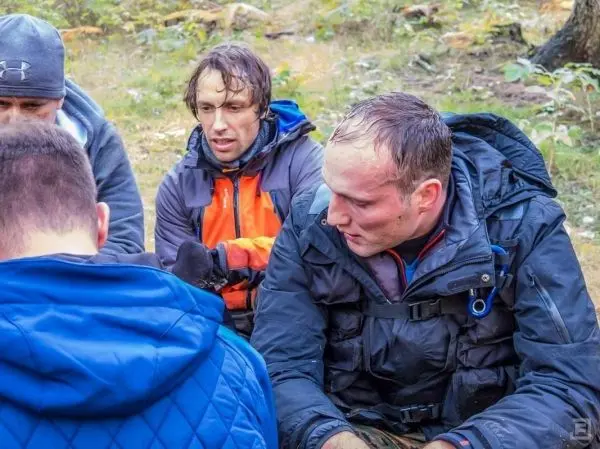 Gruppendiskussion im Freien, Teilnehmer in wetterfester Kleidung, konzentrierte Gesichter