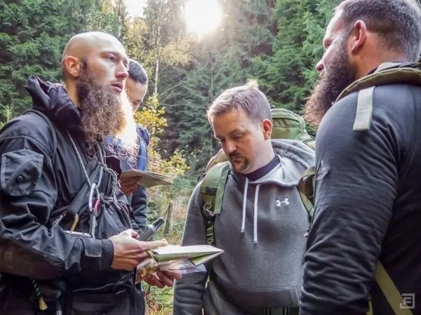 Gruppendiskussion über Karten und Navigation im Wald mit Rucksäcken