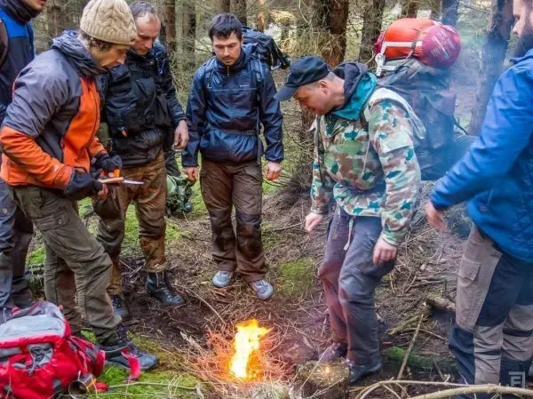 Kleine Flamme brennt zwischen mehreren Personen im Wald
