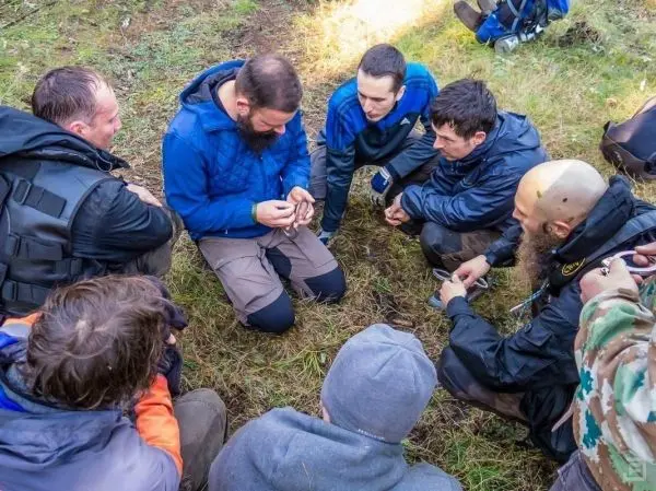 Männergruppe sitzt im Kreis und beobachtet eine Technikdemonstration
