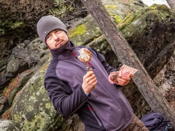 Mann hält einen Löffel mit Essen in der Hand, steht vor einer Felswand