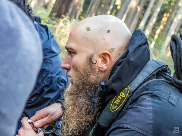Mann mit Bart und Glatze konzentriert sich auf Ausrüstung in Waldumgebung