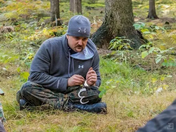Mann sitzt im Gras und hält eine Schlinge in der Hand