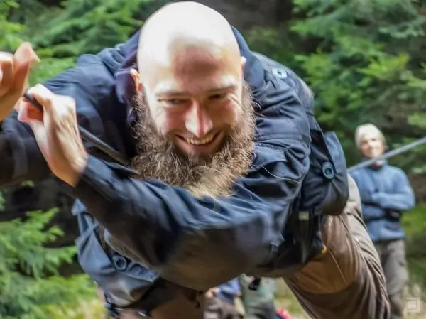 Mann überquert selbstgebaute Seilbrücke mit einem Lächeln im Gesicht