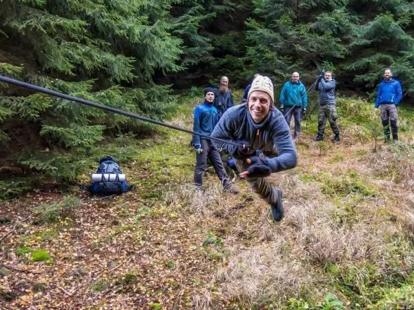 Mann überquert selbstgebaute Seilbrücke, während andere zuschauen
