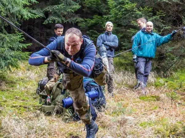 Mann überquert selbstgebaute Seilbrücke, während andere zuschauen
