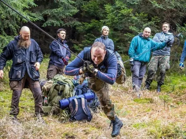 Mann überquert selbstgebaute Seilbrücke, während andere zuschauen