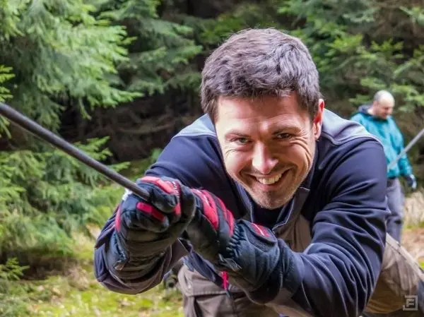 Mann zieht an einem Seil während einer Seilquerung im Wald
