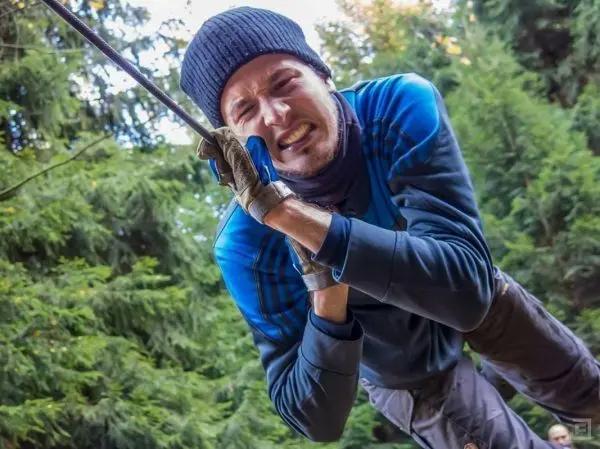 Mann zieht sich an einem Seil hoch, umgeben von Bäumen